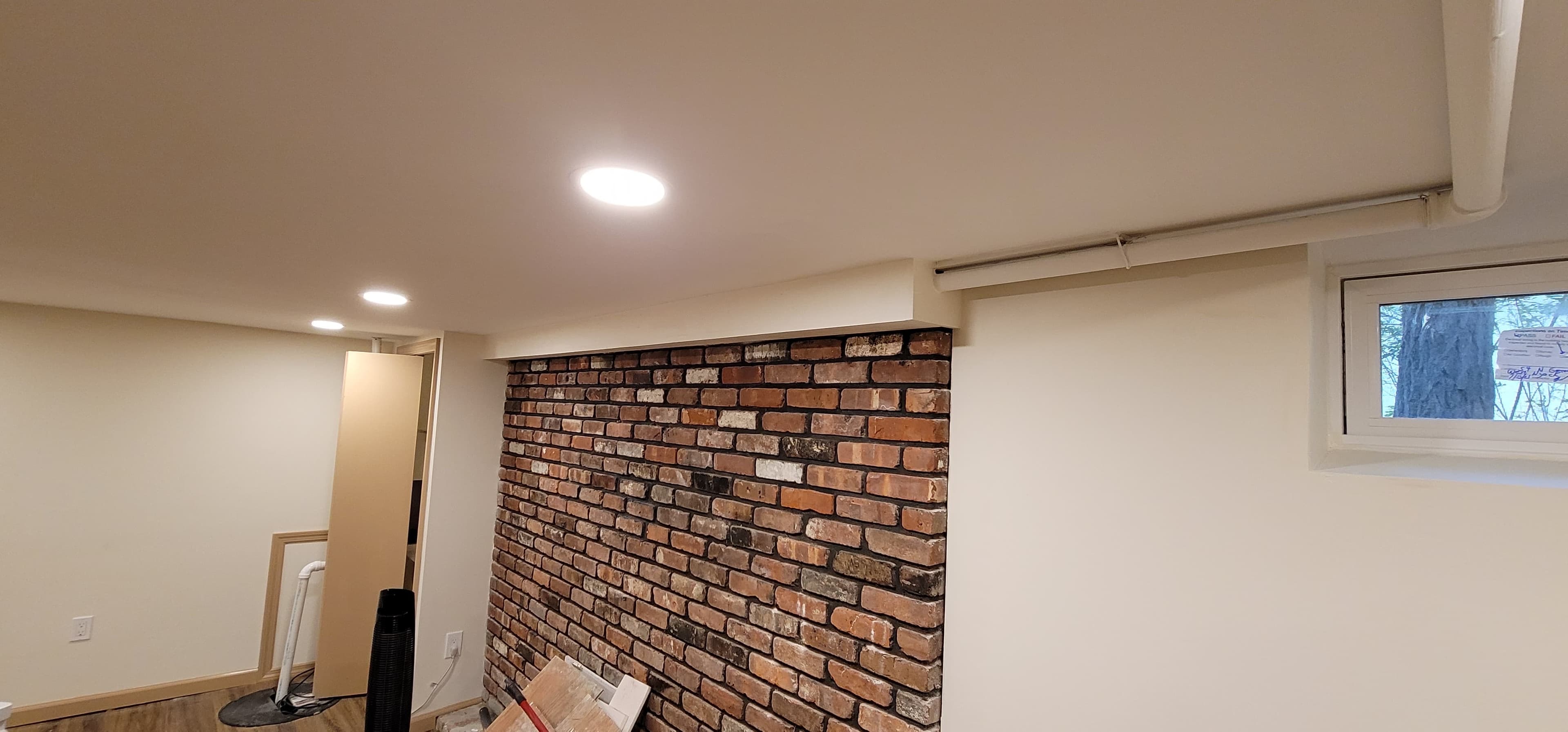 Finished basement with exposed brick accent wall and recessed lighting in Rockland County NY