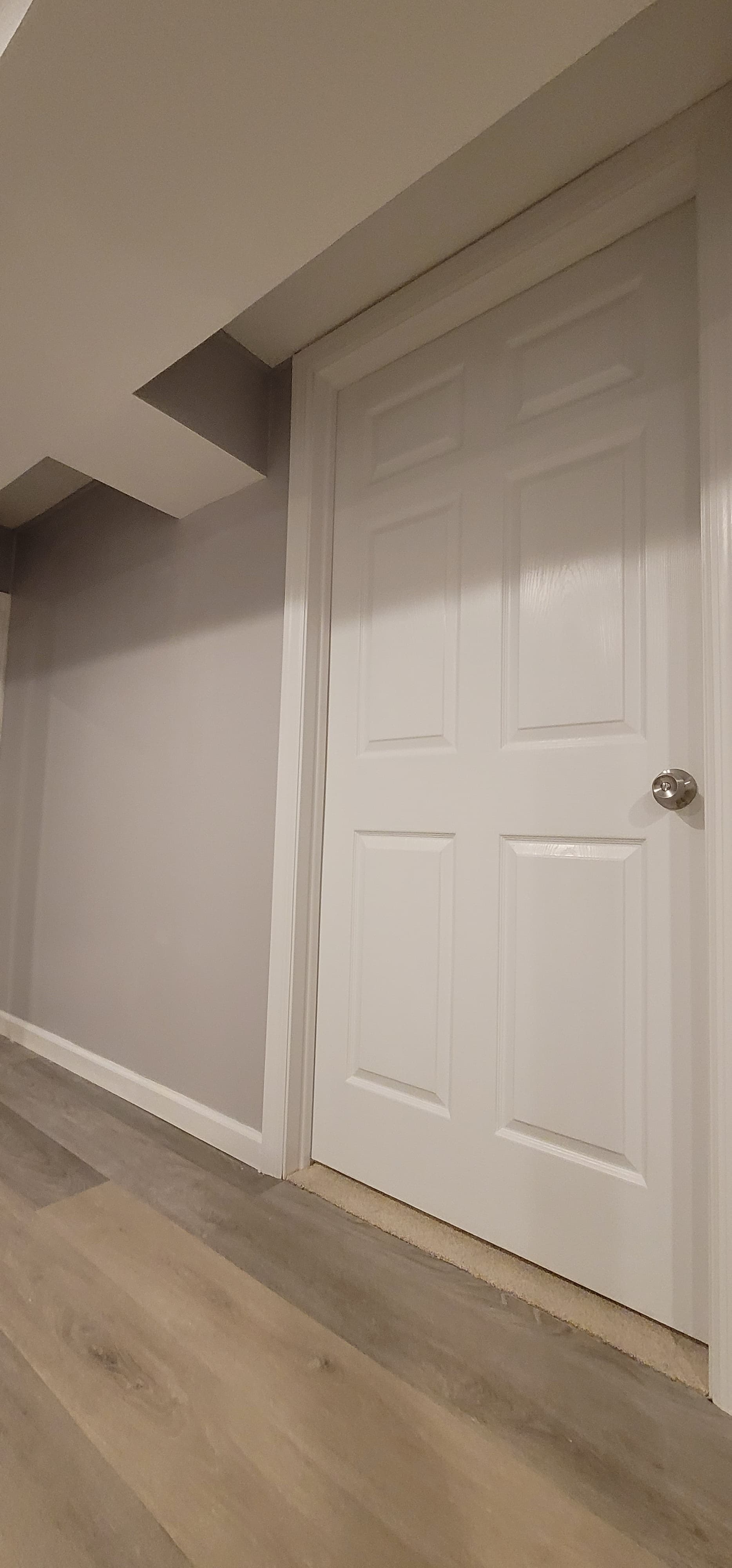 Finished basement hallway with gray walls, LVP flooring, and white door and trim, Rockland County NY