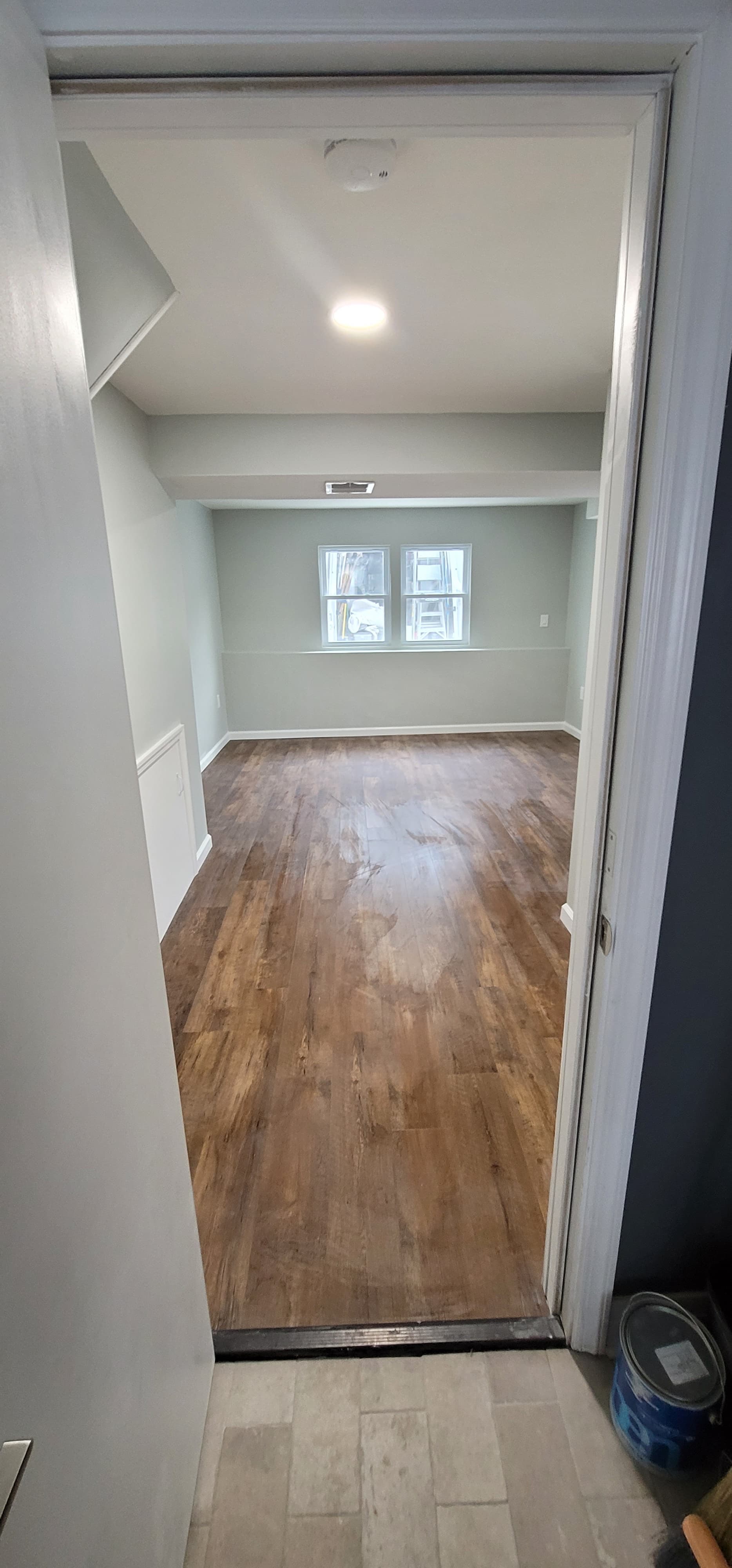 View through doorway into finished basement room with dark LVP flooring and gray walls, Rockland County NY